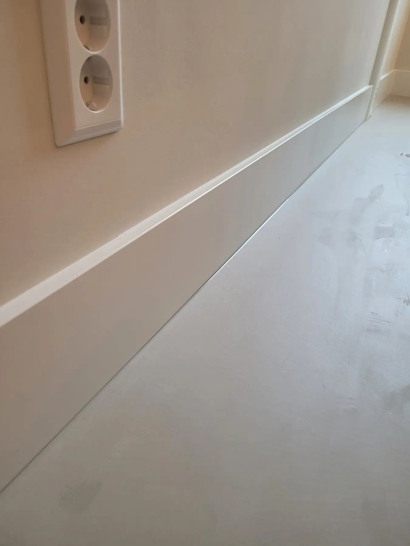 Detail van een strak geplaatste witte MDF-plint