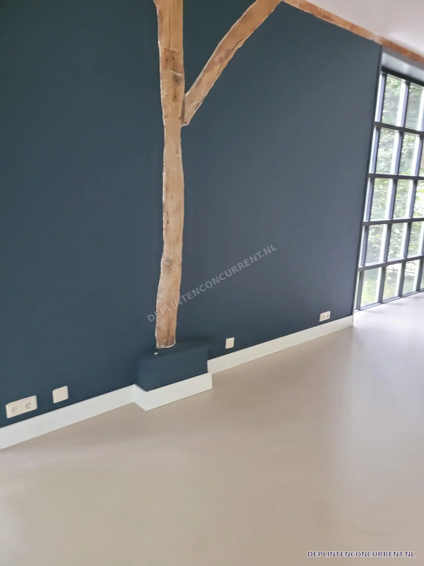 Hoge witte plinten langs een blauwe wand